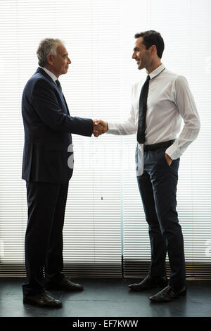 A piena lunghezza ritratto di due imprenditori in piedi, sorridente e stringono le mani Foto Stock