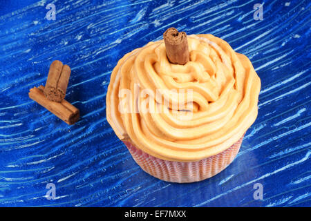 La carota e la cannella cupcake su un piatto di vetro su uno sfondo blu. Foto Stock