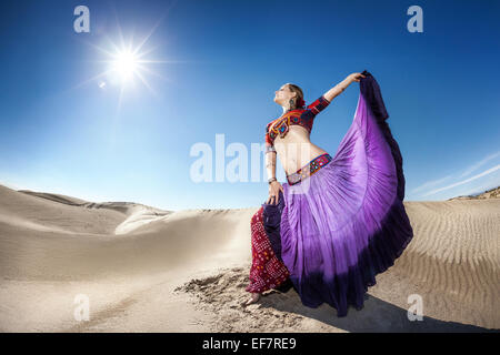Donna in gonna viola in ballo nel deserto di cielo blu Foto Stock