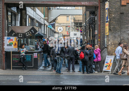 La folla di persone presso le bancarelle del mercato e i negozi a Brick Lane a Londra, su un affollato Sabato mattina - solo uso editoriale Foto Stock