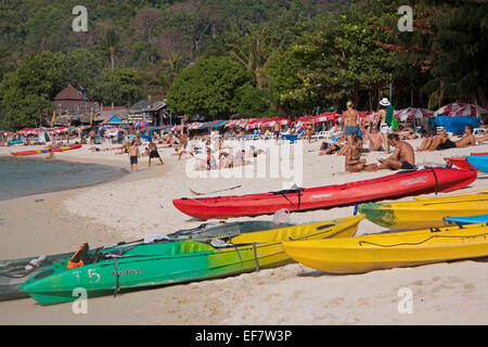 Canoe colorate e i turisti occidentali a prendere il sole sulla spiaggia di uno dei Ko Phi Phi Islands, nel sud della Thailandia Foto Stock