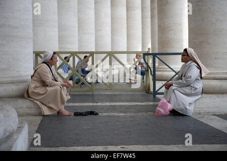 Due monache in appoggio e parlare dalle colonne del Colonnato di Piazza San Pietro, Città del Vaticano, Roma, Italia. Foto Stock