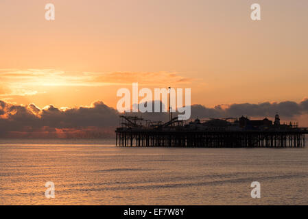 Sole che tramonta dietro la silhouette del Palace Pier Foto Stock