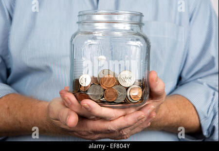 Chi detiene un barattolo di vetro contenente gli Stati Uniti monete e denaro. Foto Stock