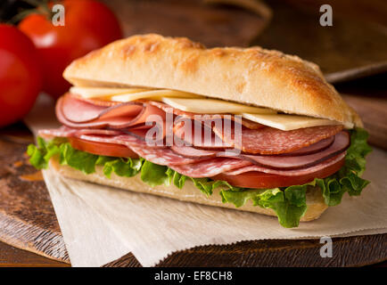 Un delizioso sandwich con affettati, lattuga, pomodoro e formaggio fresco sul pane ciabatta. Foto Stock
