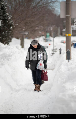 Lexington, MA, Stati Uniti d'America, 28 gen 2015. Donna che cammina sul marciapiede su Massachusetts Avenue in Lexington, MA il giorno dopo una massiccia tempesta di neve ha colpito orientale e Massachusetts centrale il Martedì, 1/27/15. Lexington è a 5 miglia a nord di Boston. Più di due metri di neve sono caduti in Boston, MA, e parti della centrale e orientale del Massachusetts svegliato da più di trenta centimetri di neve dopo la bufera di neve che è stato classificato come il sesto più grande tempesta di neve nell'area di Boston dal 1935. Foto di JBCN/ Alamy Live News Foto Stock