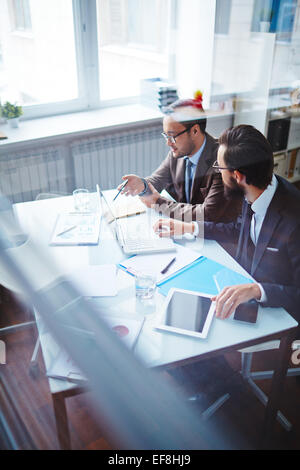 Due partner commerciali a discutere di piani e strategie in ufficio Foto Stock