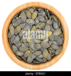 Sgusciate i semi di zucca in una ciotola di legno isolato od uno sfondo bianco. Vista dall'alto. Foto Stock