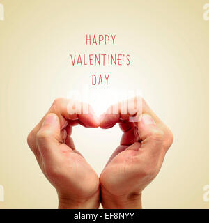 Le mani di un giovane uomo formando un cuore e la frase felice il giorno di san valentino scritto su uno sfondo beige Foto Stock