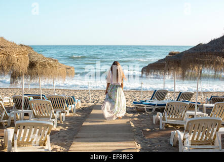 Vista posteriore del giovane donna bionda passeggiate verso la spiaggia Foto Stock