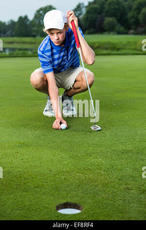 Ragazzo adolescente ponendo la sfera sul raccordo a T sul campo da golf Foto Stock