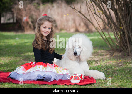 Ritratto di ragazza (6-7) e il barboncino bianco sulla coperta picnic Foto Stock