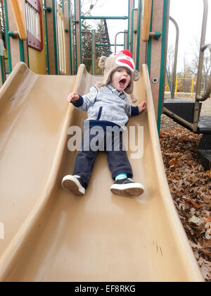 Ragazzo scorrevole sul parco giochi Foto Stock