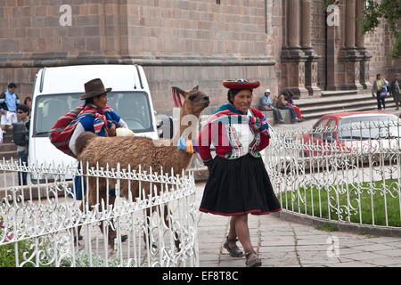 Cosco, Perù street scene di due donne peruviane in abito tradizionale, uno che porta un giovane bambino, passeggiate con gusto alpacca Foto Stock