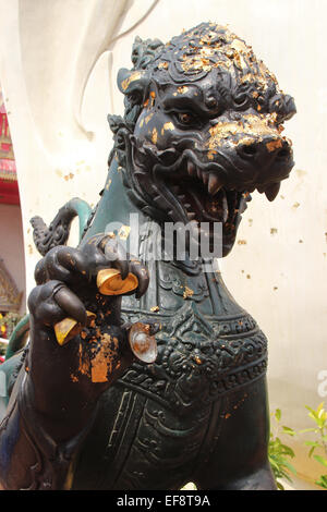 Foglie di oro sono stati bloccati su una statua di Lion installato nel cortile del Wihan Phra Mongkhon Bophit in Ayutthaya, Thailandia. Foto Stock