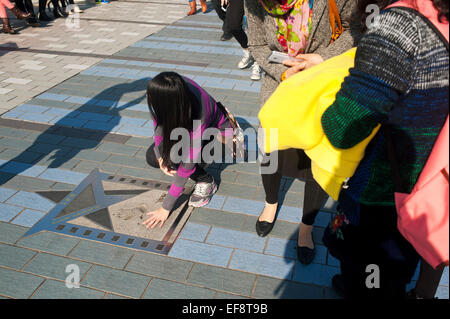 Hong Kong 2015 - ragazza mette le mani per handprints filmstar Jackie Chan su Hong Kong s Viale delle Stelle a Kowloon Foto Stock