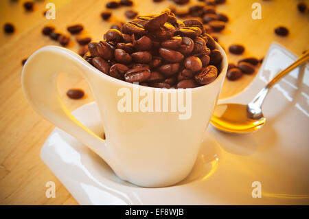 Primo piano di una tazza di caffè piena di caffè torrefatto in grani Foto Stock