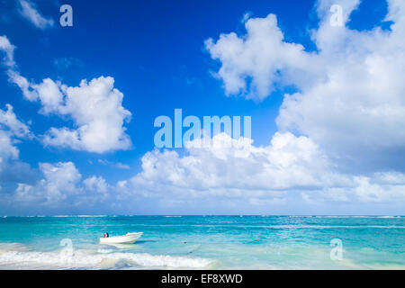 Di piccole dimensioni e di colore bianco con una barca a motore galleggianti ormeggiate vicino alla costa dell'Oceano Atlantico, Repubblica Dominicana. Punta Cana Foto Stock