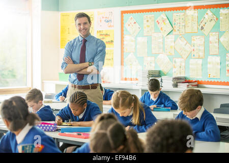 Ritratto del maestro sorridente e bambini di scuola elementare in aula Foto Stock