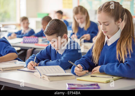 Scuola elementare i bambini che lavorano al banco in aula durante la lezione Foto Stock