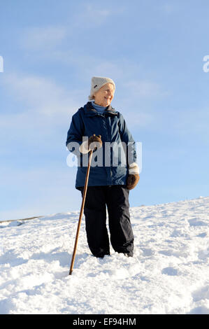 Signora anziana a piedi nella neve nel North York Moors National Park Foto Stock