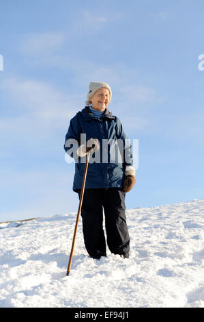 Signora anziana a piedi nella neve nel North York Moors National Park Foto Stock