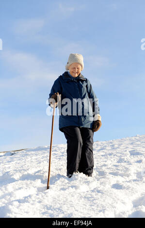 Signora anziana a piedi nella neve nel North York Moors National Park Foto Stock