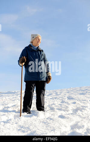 Signora anziana a piedi nella neve nel North York Moors National Park Foto Stock