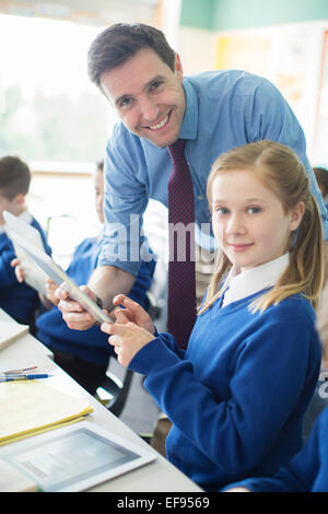 Ritratto di insegnante di sesso maschile con i suoi allievi in aula utilizzando tablet pc Foto Stock