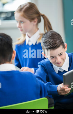 Bambini di scuola elementare blu che indossano uniformi scolastiche in aula Foto Stock