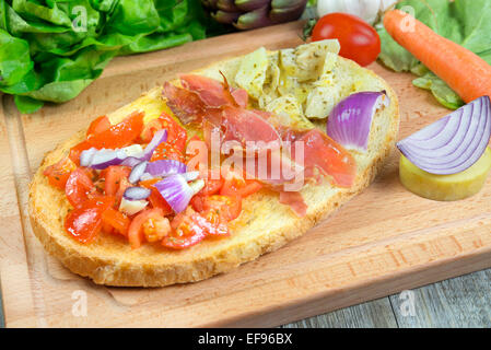 Toscana maxi bruschetta con pomodori,carciofo,speck,cipolle,e olio di oliva Foto Stock