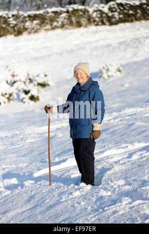 Signora anziana a piedi nella neve nel North York Moors National Park Foto Stock