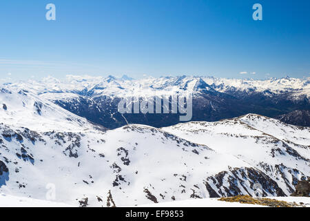 Ampio angolo di visione di una stazione sciistica in distanza con eleganti vette derivanti dall'arco alpino a fine stagione invernale. Foto Stock