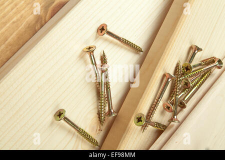 Pila di viti su un sfondo di legno. Foto Stock