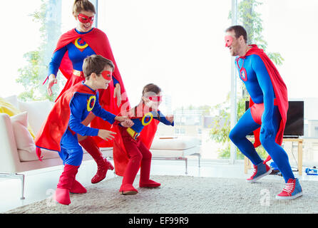 Famiglia di supereroi che si rincorrono in salotto Foto Stock