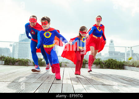 Famiglia di supereroi giocando sul tetto della città Foto Stock