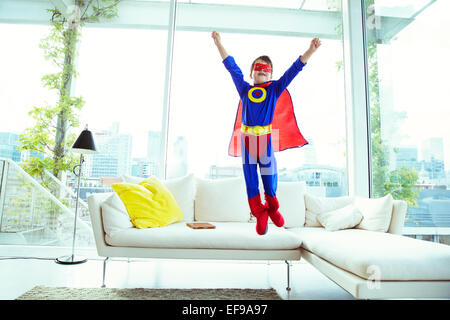 Ragazzo il supereroe che salta fuori da salotto divano Foto Stock