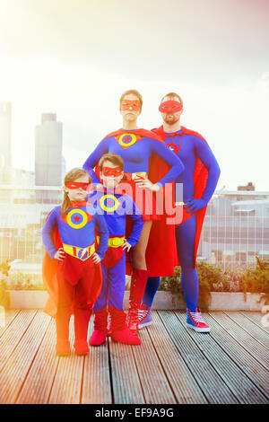 Famiglia di supereroi in piedi sul tetto della città Foto Stock