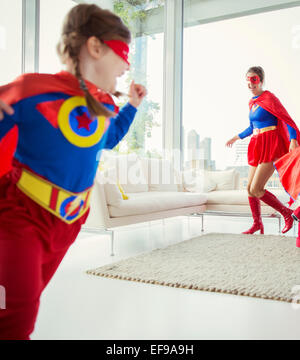 Famiglia di supereroi che si rincorrono in salotto Foto Stock