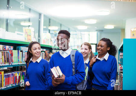 Allegro studenti blu che indossano uniformi di scuola a piedi attraverso la libreria Foto Stock