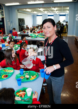 Pranzo al Regno Unito Membro della Scuola Primaria lady cena servendo i bambini della scuola elementare alla scuola primaria Foto Stock