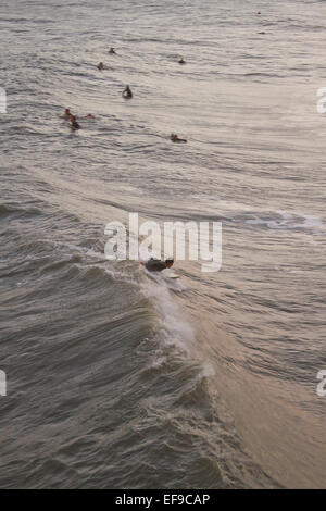 Una vista da sopra di un surfista maschio scorre un oceano onda off di uragano Sandy come altri surfers watch Foto Stock