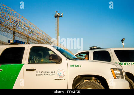 Incorniciato da recinzione internazionali per Stati Uniti/Messico frontiera e due Pattuglia di Confine SUV di fronte alla colonia Libertad distretto di Tijuana, una televisione torre di avvistamento sondaggi tentativi di immigrazione illegale. Nota il filo di rasoio sulla parte superiore della recinzione. Foto Stock