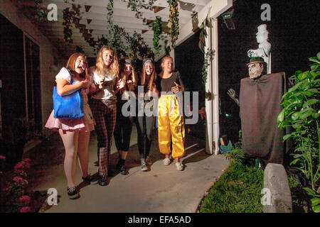 Urlando appropriatamente in un fantasma (destra) cinque giovani donne di entrare nello spirito di una notte di Halloween "Haunted Mansion' in Lake Forest, CA. Foto Stock