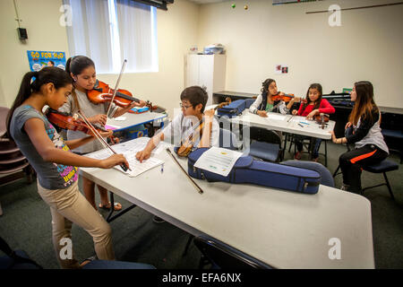 Asian alta scuola di musica di volontariato mentor insegna violino a ispanica ragazze adolescenti a una community center di Santa Ana CA. Nota spartiti. Foto Stock