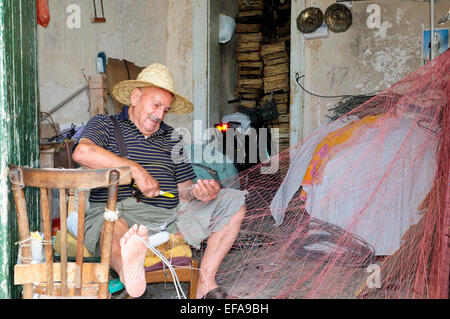 Pulizia del pescatore le reti da pesca al porto, Trapani, Sicilia Foto Stock