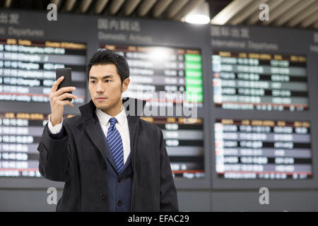 Giovane imprenditore utilizzando smart phone in aeroporto Foto Stock