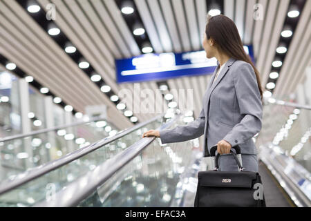 Giovane imprenditrice con la valigia in Escalator Foto Stock