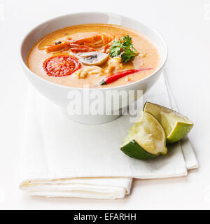 Piccante zuppa tailandese Tom Yam con peperoncino e calce su sfondo bianco Foto Stock