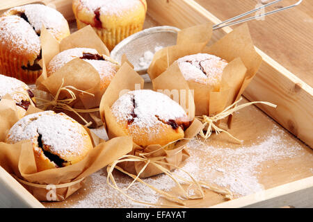 Muffin con marmellata spolverati con zucchero a velo sul vassoio in legno Foto Stock